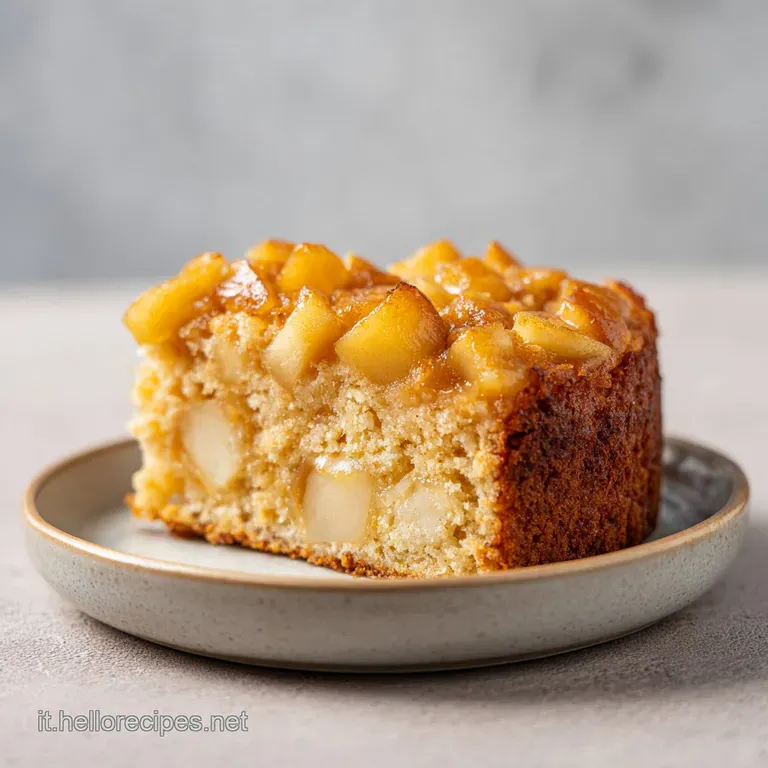 Una fetta di torta morbida su piatto bianco, con mele caramellate dorate e una texture soffice e leggera.
